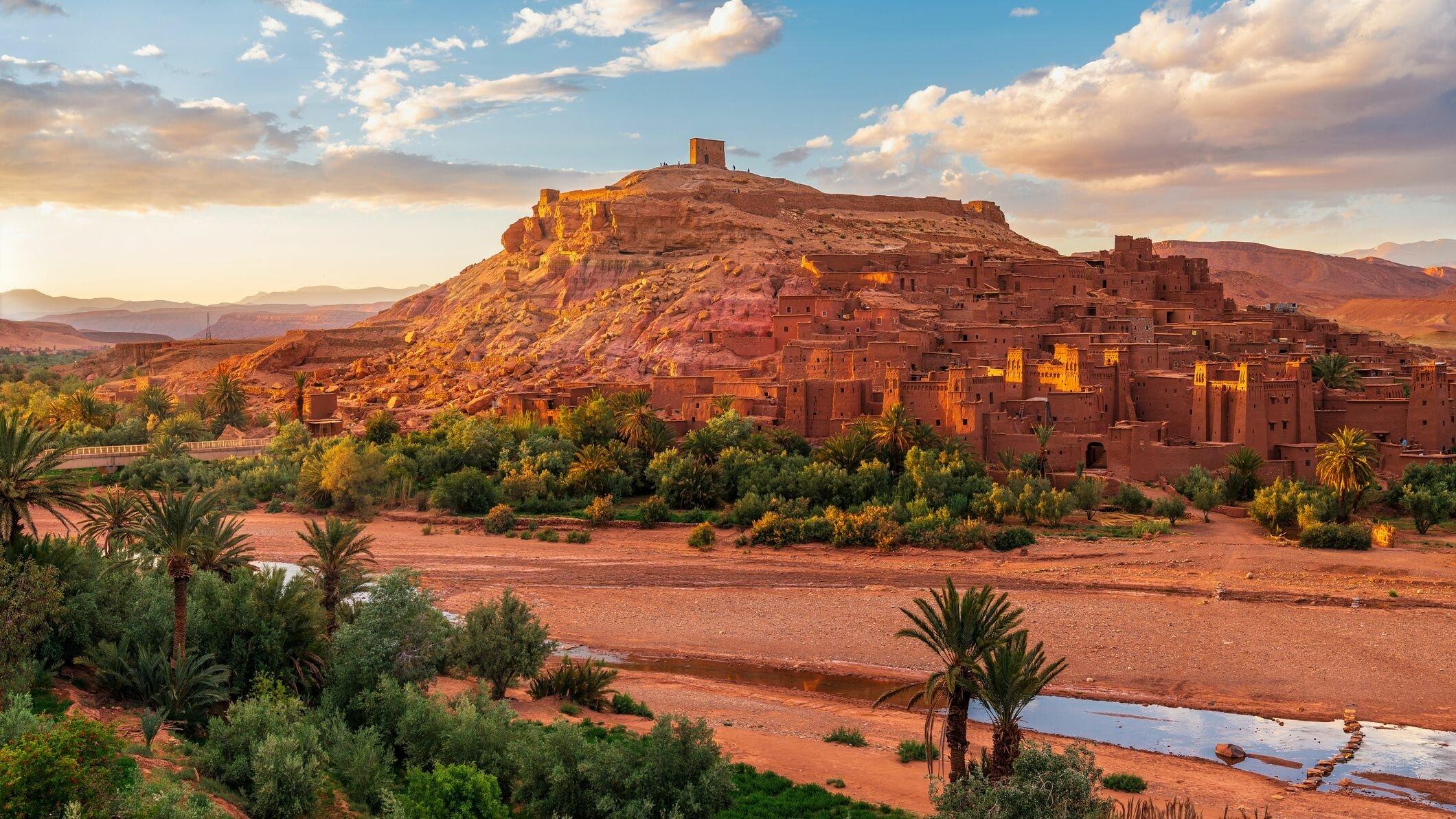Ait Ben Haddou kasbah above a palm oasis under a blue sky